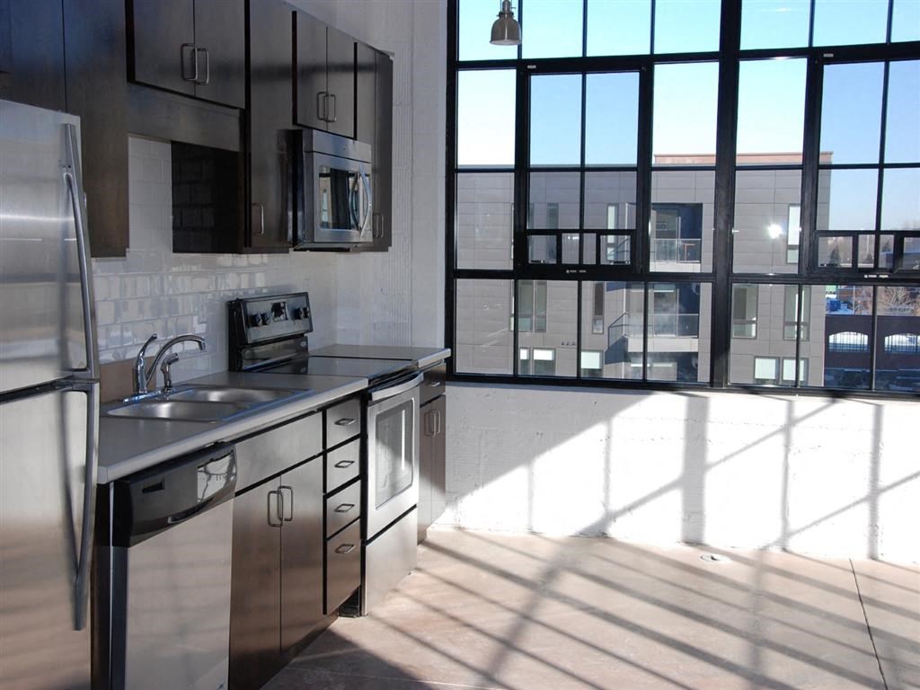 A kitchen with stainless steel appliances and a large window.at Gurley Lofts, Minneapolis, MN 55401
