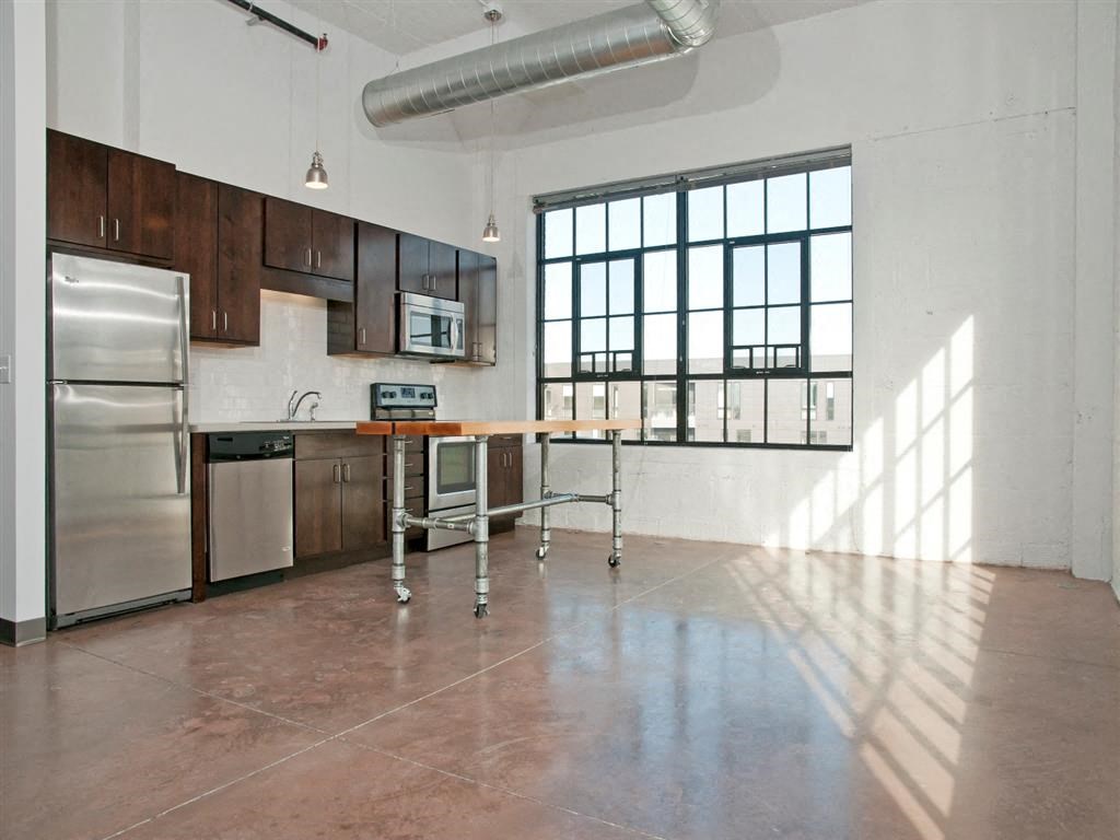 A kitchen with brown cabinets and a stainless steel refrigerator.at Gurley Lofts, Minnesota