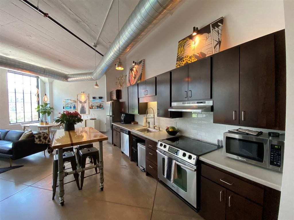 A kitchen with a black stove top oven and a black microwave.at Gurley Lofts, Minnesota, 55401