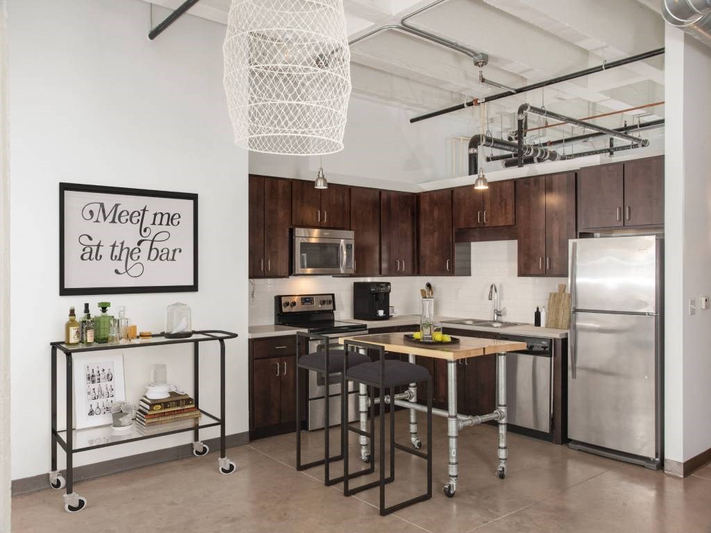 A kitchen with a fridge, stove, and bar cart.at Gurley Lofts, Minnesota