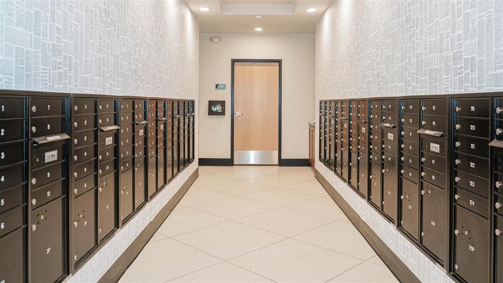 A hallway with a row of lockers on both sides and a door at the end at The Bessemer at Seward Commons Apartments, Minneapolis