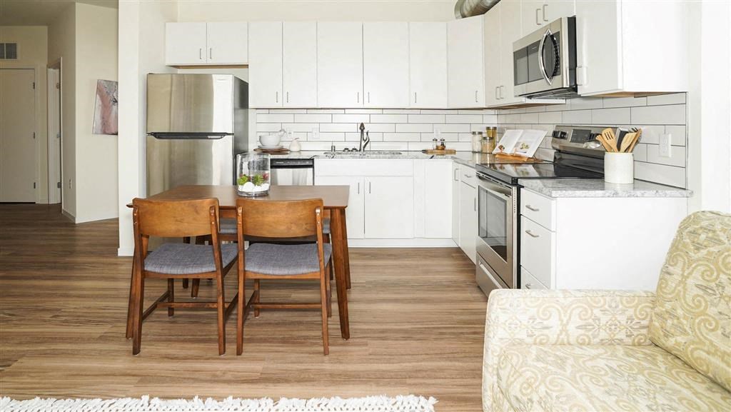 A kitchen with a table and chairs in the middle of the room at The Bessemer at Seward Commons Apartments, Minnesota