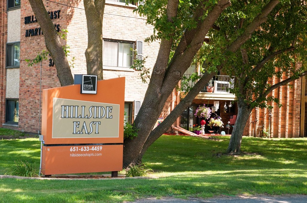 a sign that says hillside east in front of a brick building