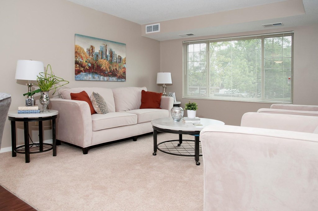 a living room with white furniture and a window