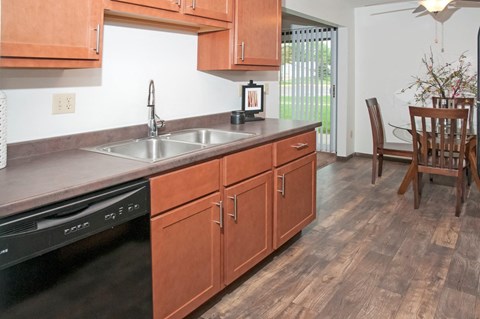 A kitchen with wooden cabinets and a black dishwasher.