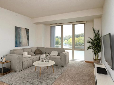 A living room with a grey sofa and a painting on the wall.