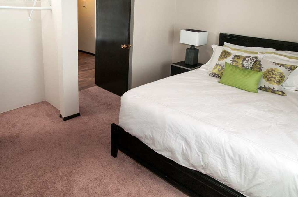 a bedroom with a white bed and a door to a bathroom