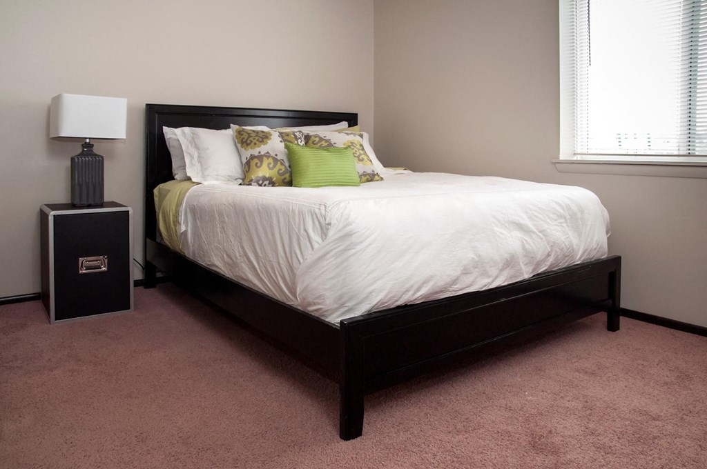 a bedroom with a bed with a white comforter and pillows