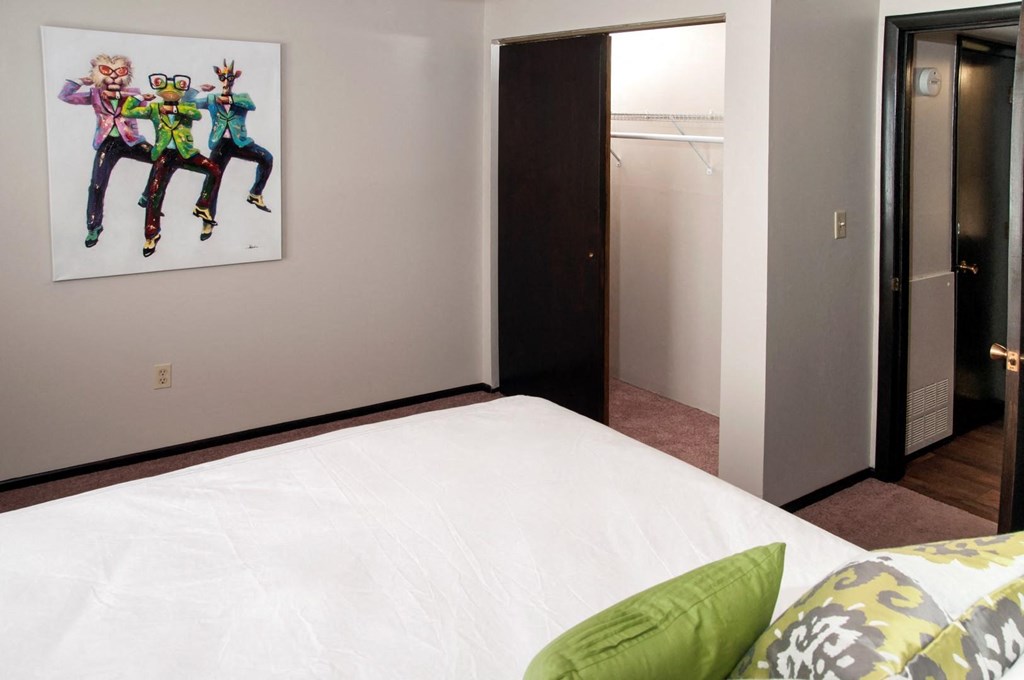 a bedroom with a white bed and a painting on the wall