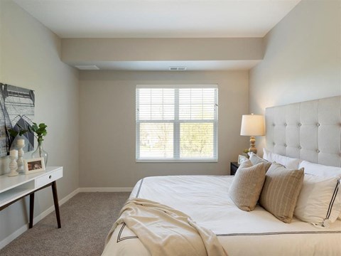 A bedroom with a large bed and a window with blinds. A bedroom with a large bed and a window with blinds at The Barnum Apartments, White Bear Lake