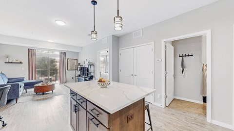 A modern kitchen with a large island and a view of the living room.