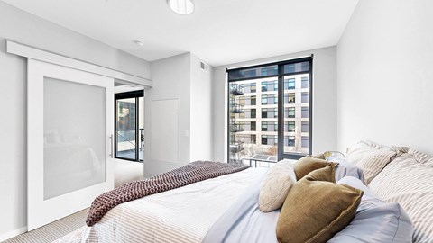 A bedroom with a large bed and a view of a cityscape through the window.