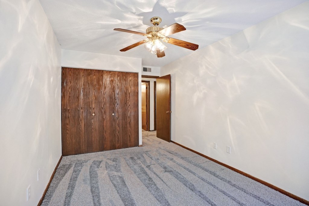 an empty room with a ceiling fan and a door