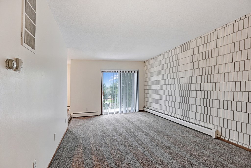 an empty living room with white walls and a sliding glass door