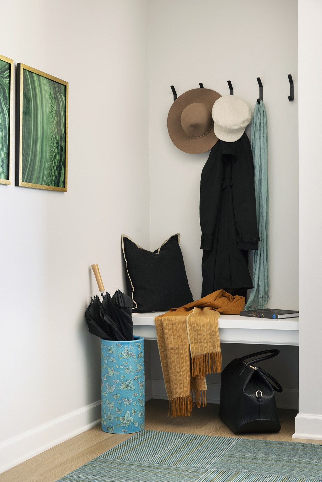 a hallway with a bench with a hat and bags on it and a coat rack