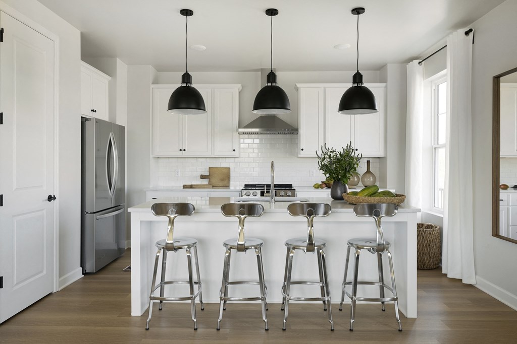 a kitchen with white cabinets and a white island with bar stools