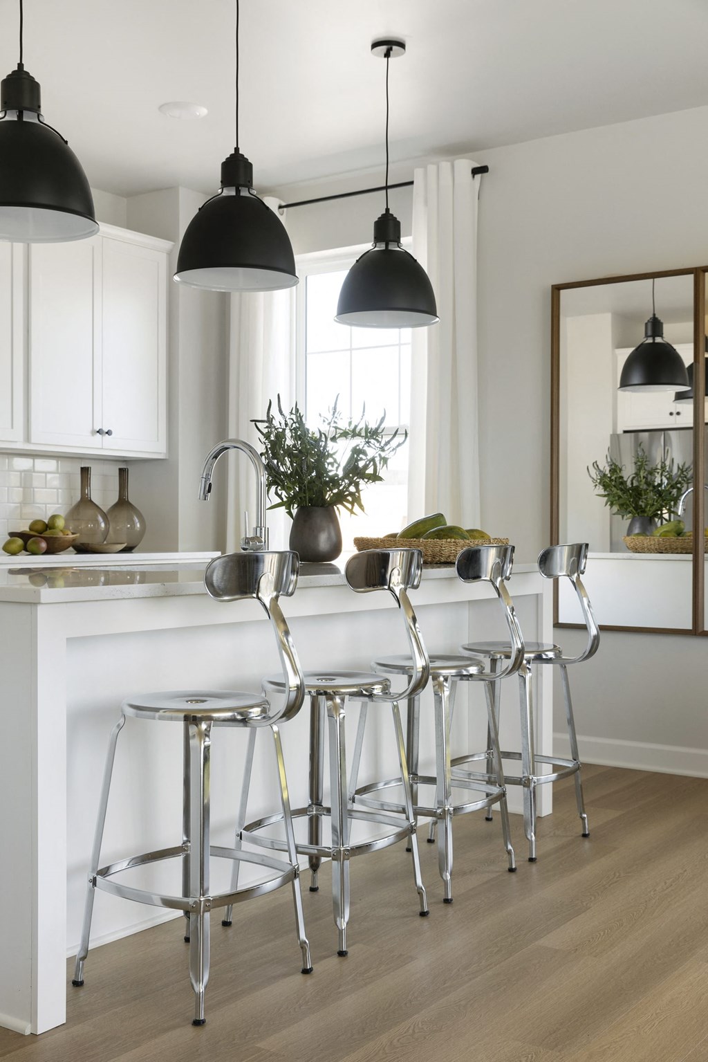 a white kitchen with bar stools and three black lamps