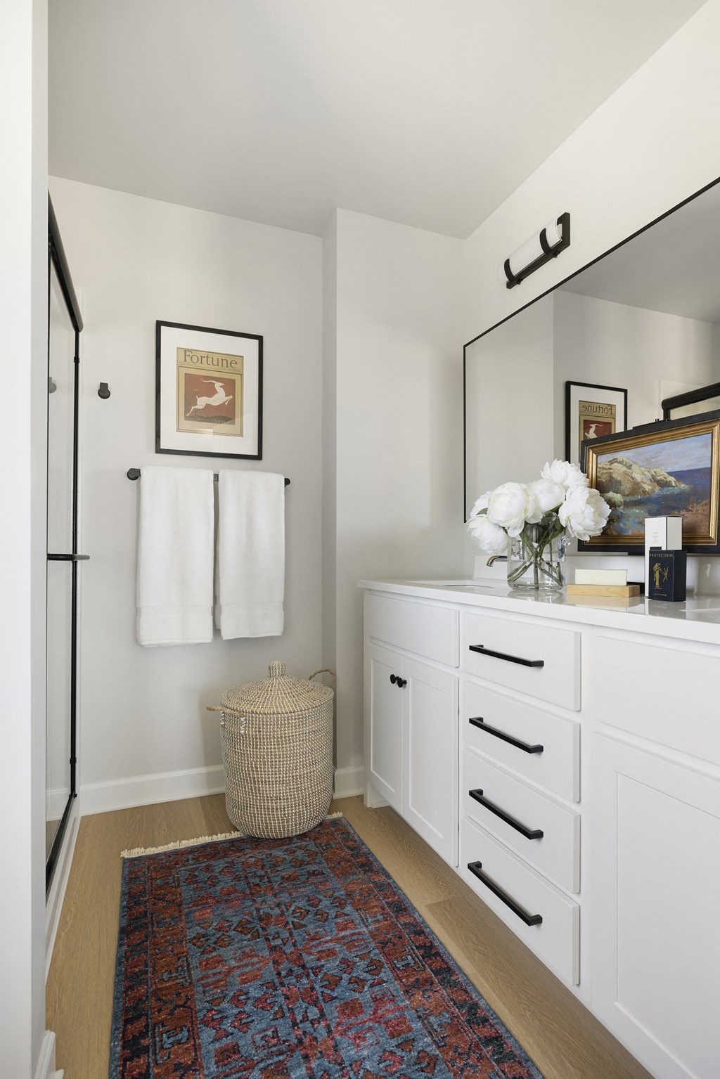 a bathroom with white cabinets and a mirror and a rug
