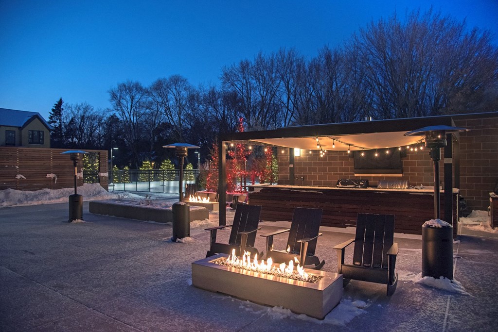 Outdoor patio with firepit, bar, and seating in the winter time at The McMillan