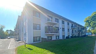 a large apartment building with balconies and a grassy area in front of it