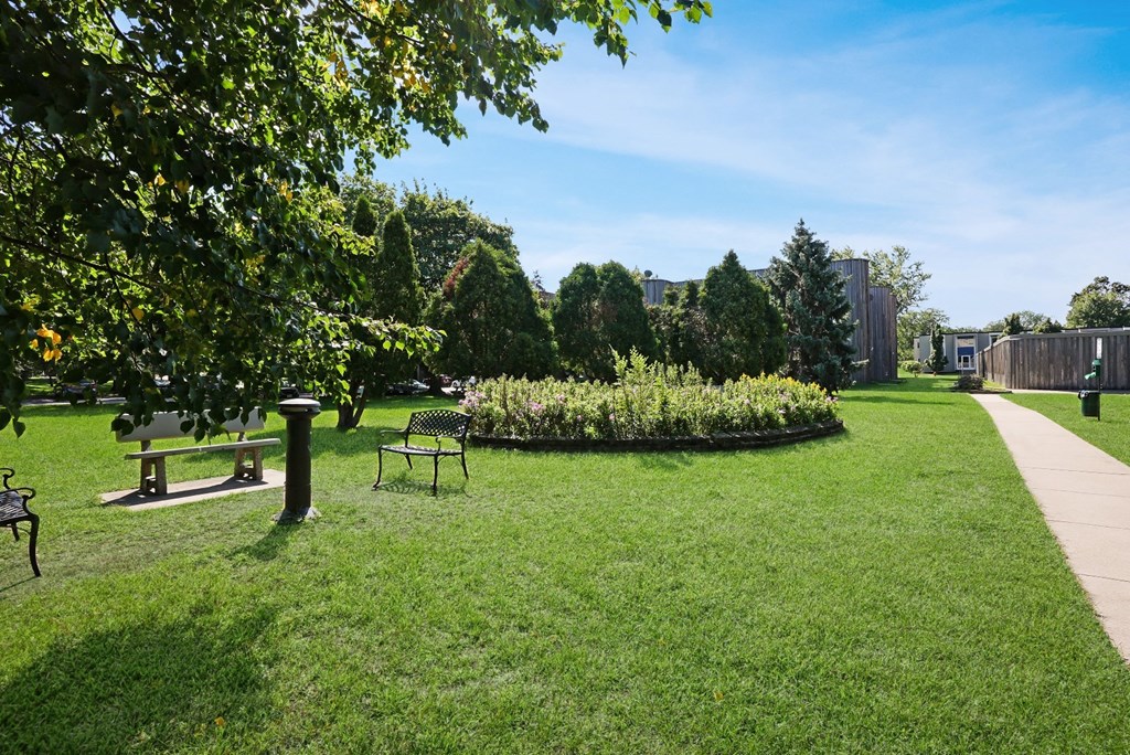 a park with benches and a garden on a sunny day