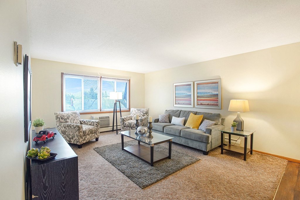 a living room with a couch and two chairs and a window