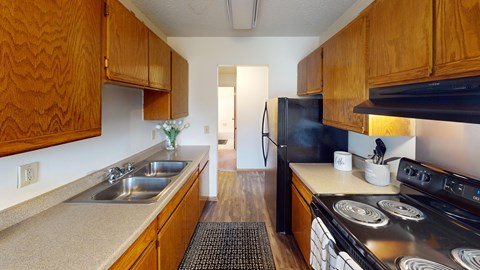 A kitchen with wooden cabinets and a black refrigerator.