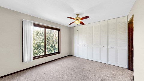 A room with a ceiling fan and a window with curtains.