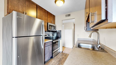 A kitchen with a stainless steel refrigerator and a microwave above the stove.