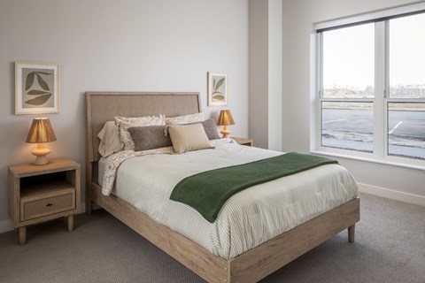 A bedroom with a large bed and two lamps.