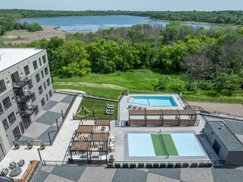 A large outdoor swimming pool with a green grassy area and a building in the background.