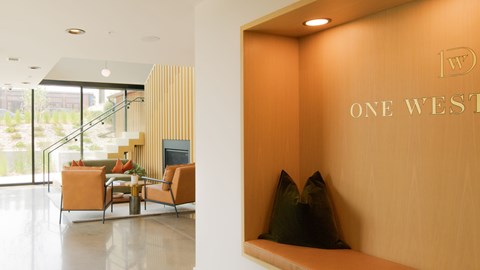 A modern living room with a sofa set and a wooden wall with the words "One West" on it.