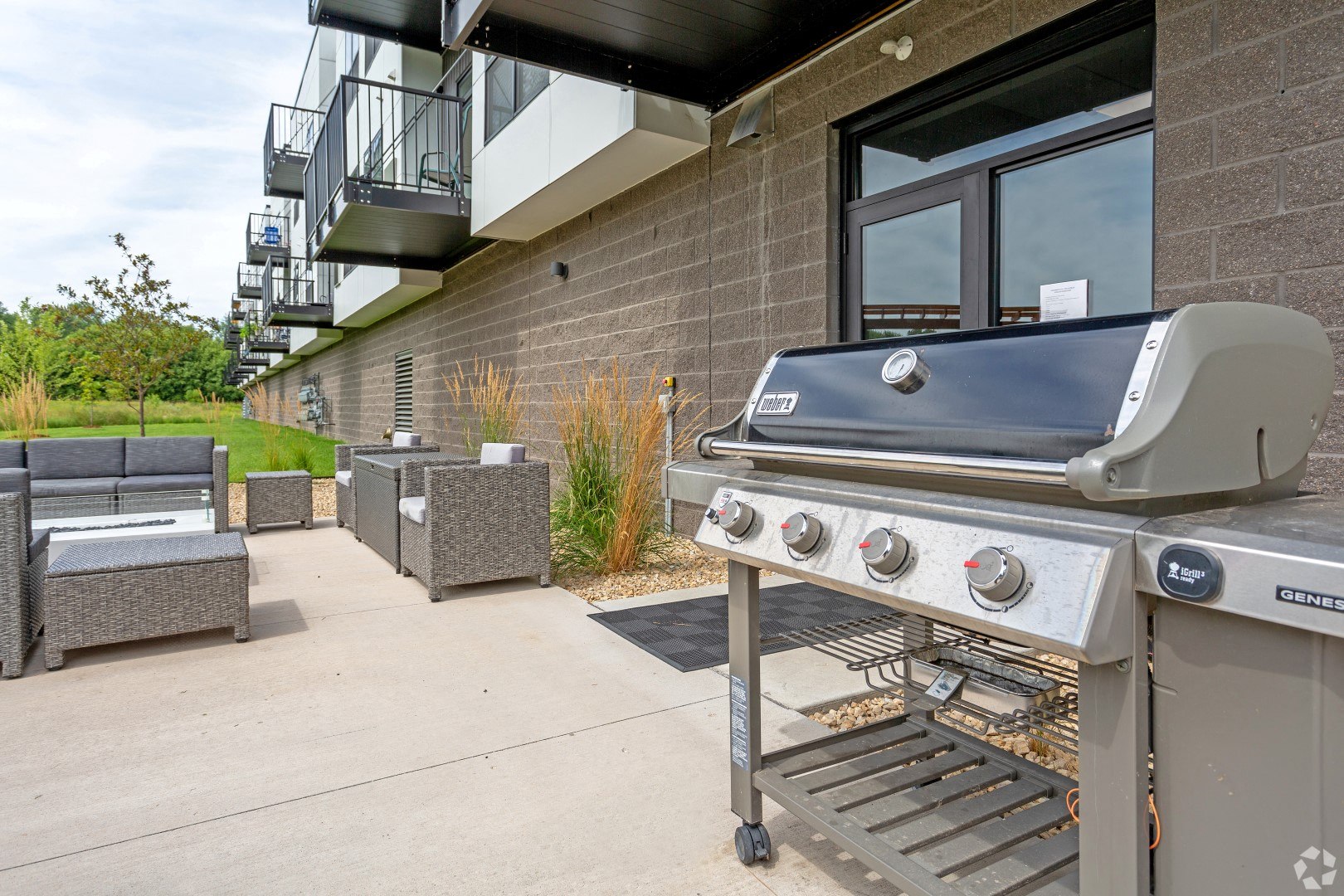 the private patio has a grill and seating area next to a building