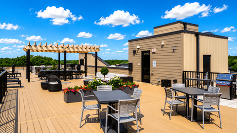 A wooden deck with a table and chairs and a building in the background.