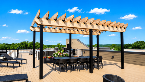 A wooden pergola with a table and chairs underneath it.
