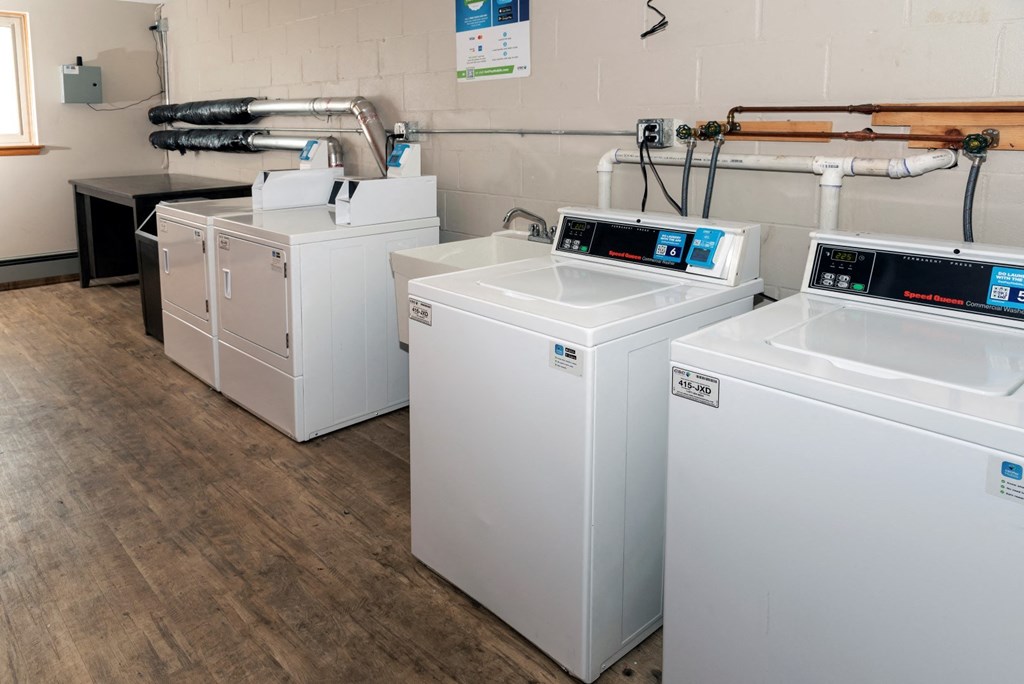 a row of washers and dryers sit in a room