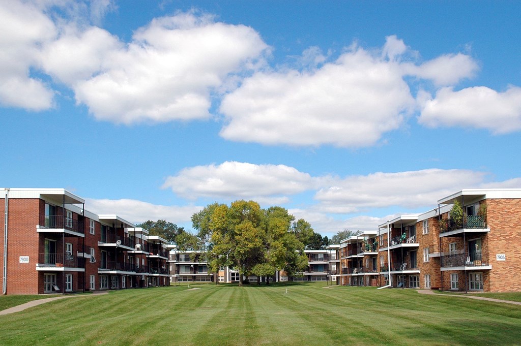 a grassy area between two rows of brick apartment buildings at Point of America Apartments,Minnesota