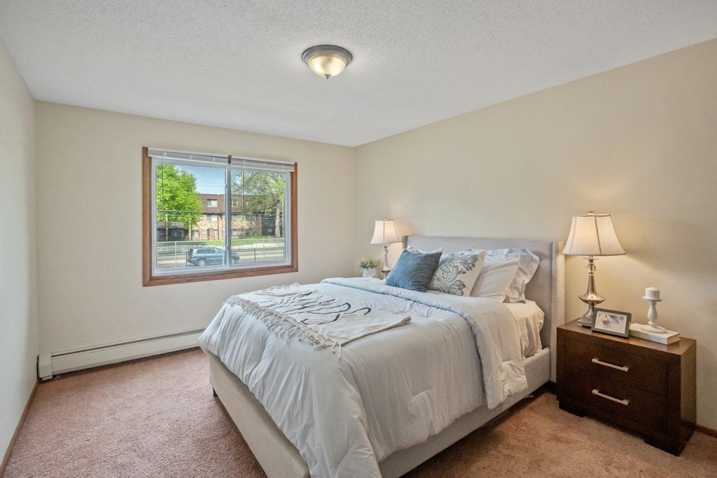 a bedroom with a large bed and a large window at Point of America Apartments,Brooklyn Park