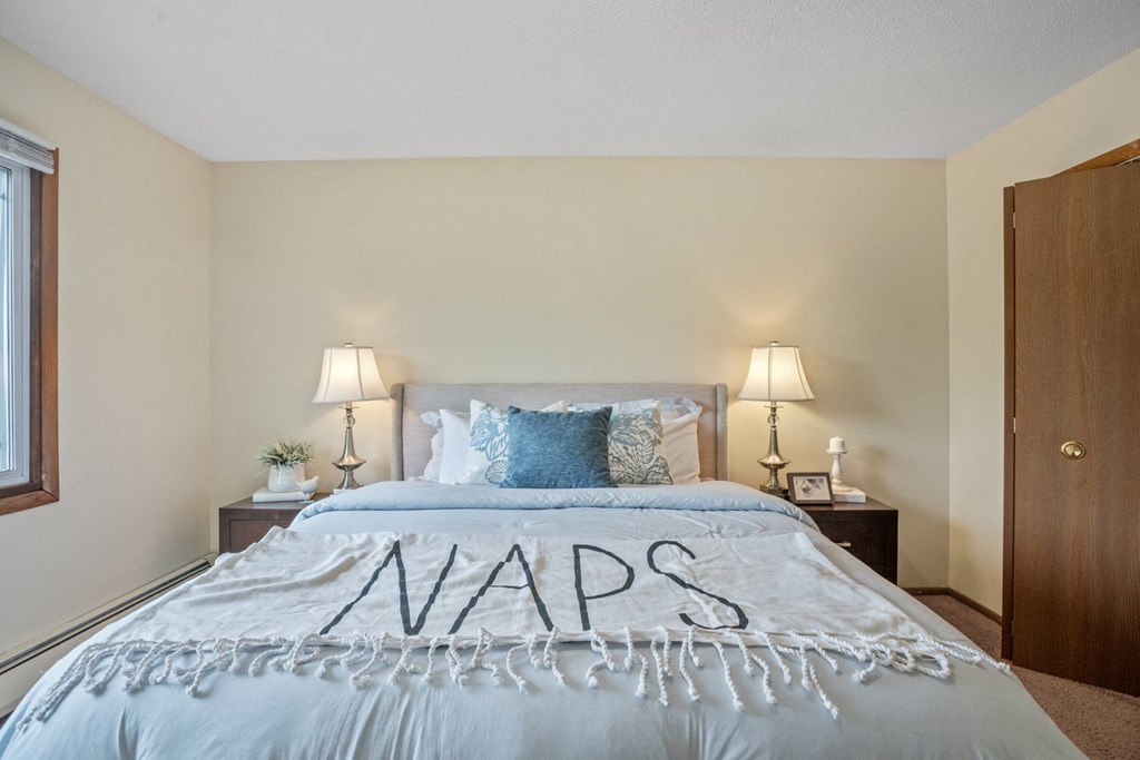 a bedroom with a bed and two nightstands at Point of America Apartments,Brooklyn Park