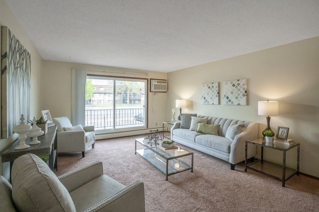 a living room with a large window and a sliding glass door at Point of America Apartments, Brooklyn Park, MN 55443