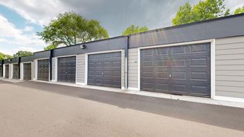 a row of garages in a parking lot with trees in the background