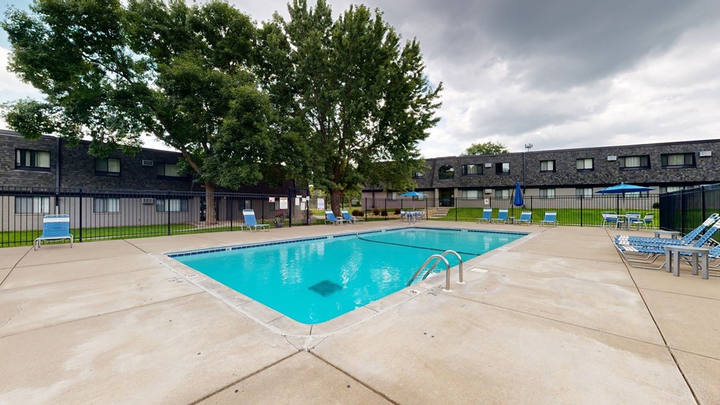 a swimming pool with chaise lounge chairs and umbrellas in front of a building