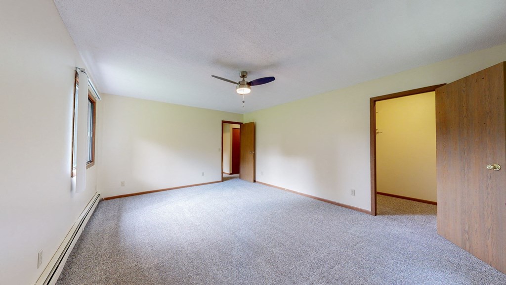 an empty living room with a ceiling fan