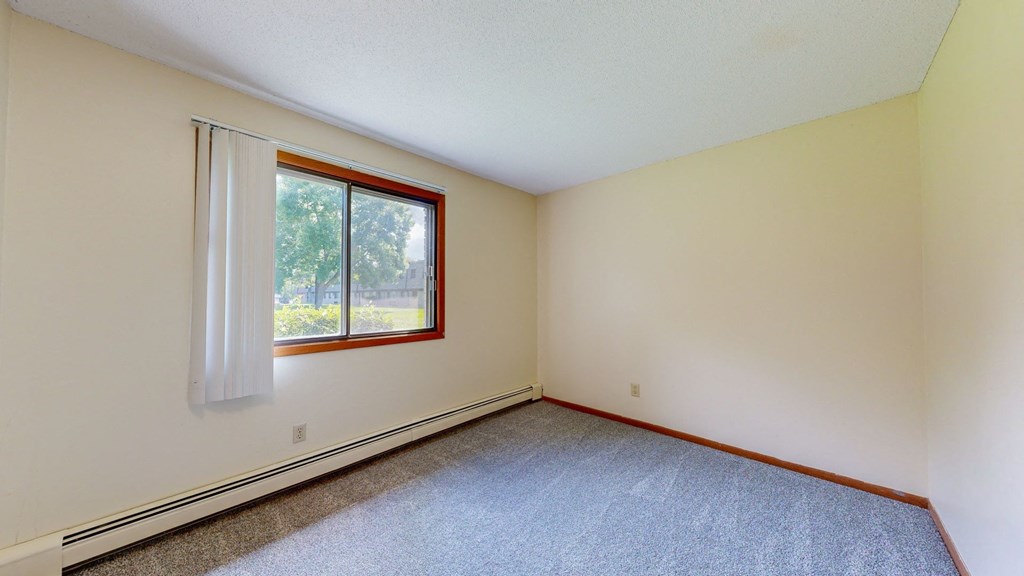 a bedroom with white walls and a window with a white curtain