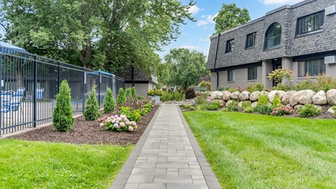 A walkway leads through a landscaped area with a building in the background.