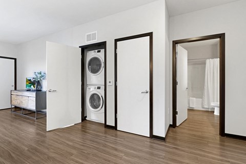 a washer and dryer in a living room with a door to a bathroom