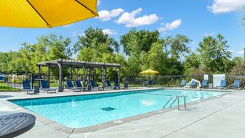 A sunny day at the pool with a yellow umbrella providing shade.
