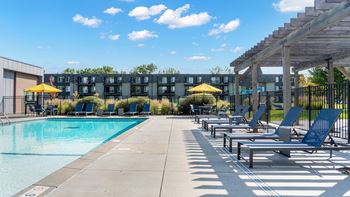 A pool area with sun loungers and a building in the background.