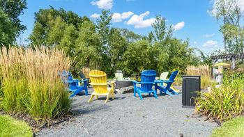 A gravel area with blue and yellow chairs and a trash can.