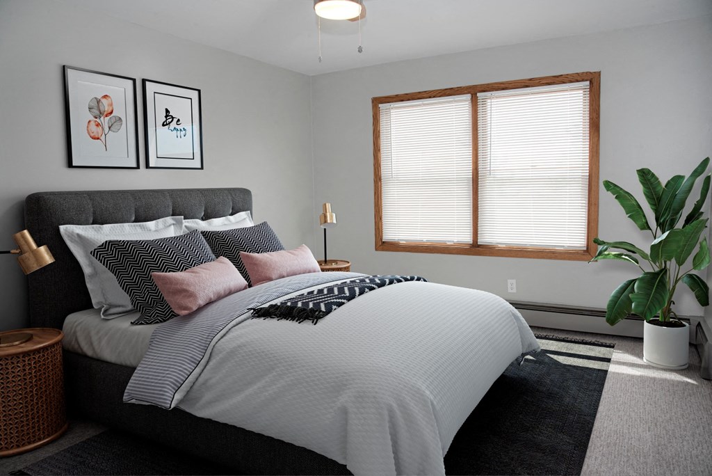 a bedroom with a bed and a window and a plant